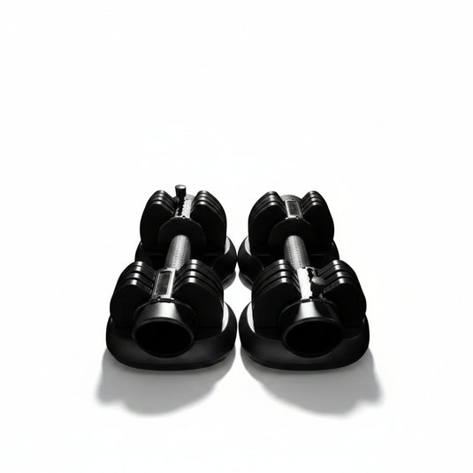 Two black adjustable dumbbells with weight markings, resting on a light gray tiled floor.